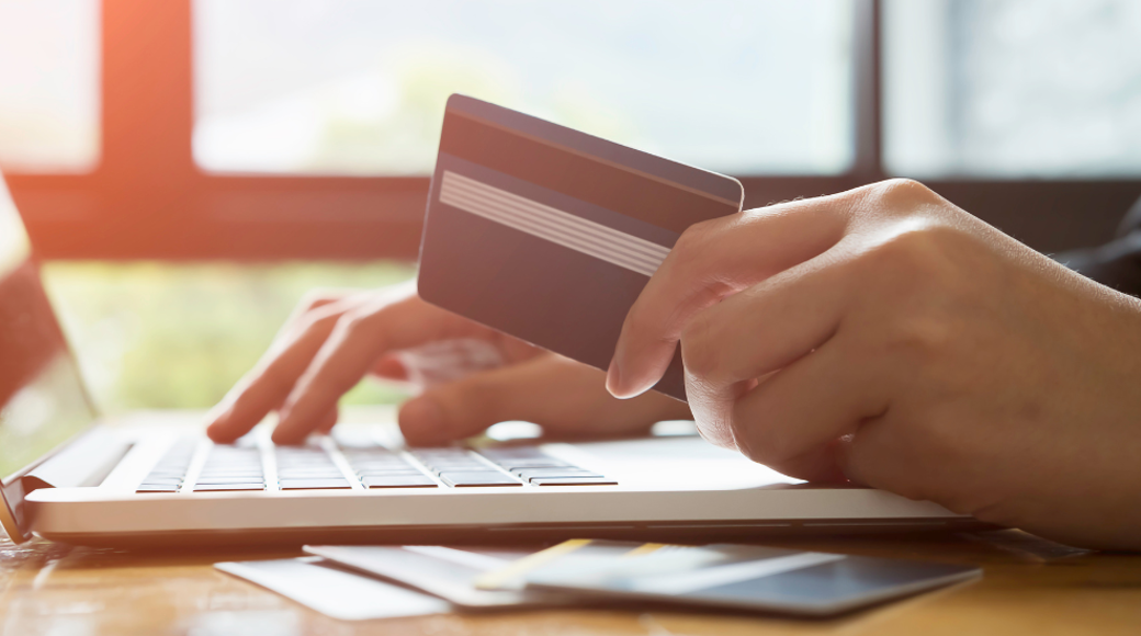 Hand Holding A Credit Card And Typing At A Laptop
