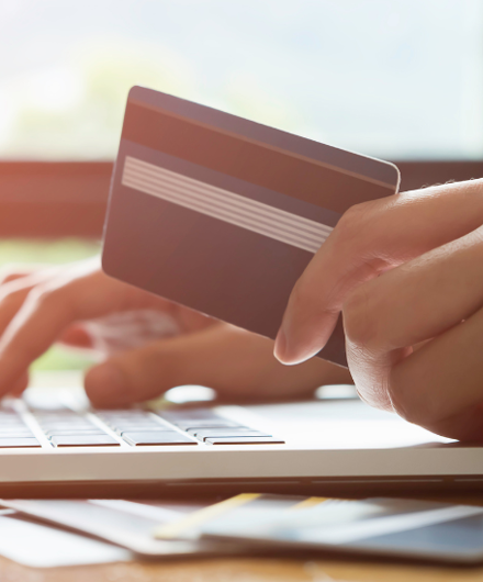 Hand Holding A Credit Card And Typing At A Laptop