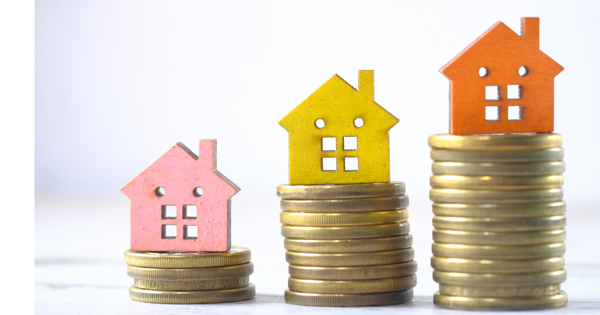 Pink, Yellow And Orange House Figure On The Top Of A Pile Of Coins Increasing Height Of Pile Each Time